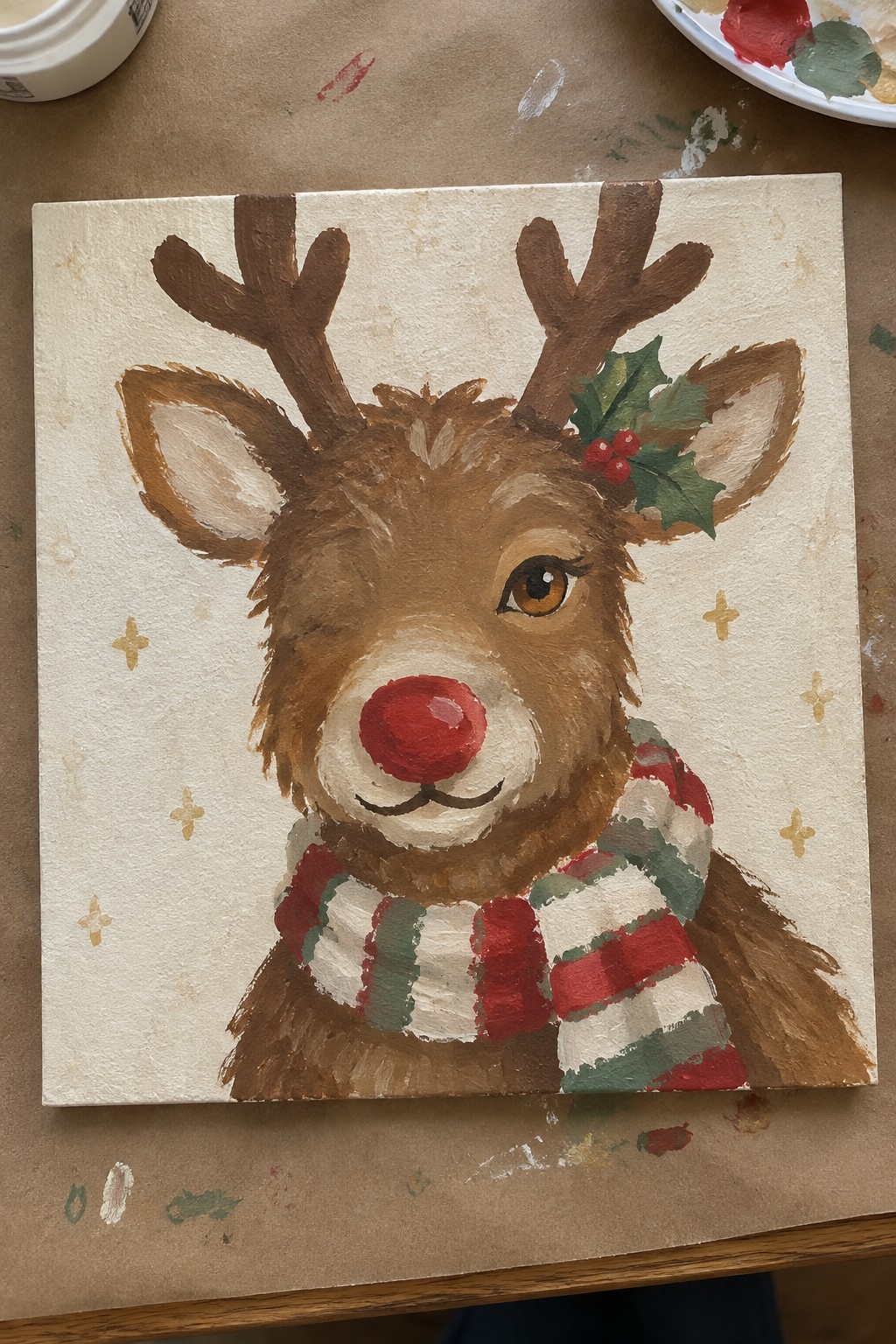 Cute painted reindeer with red nose, striped scarf, antlers and holly