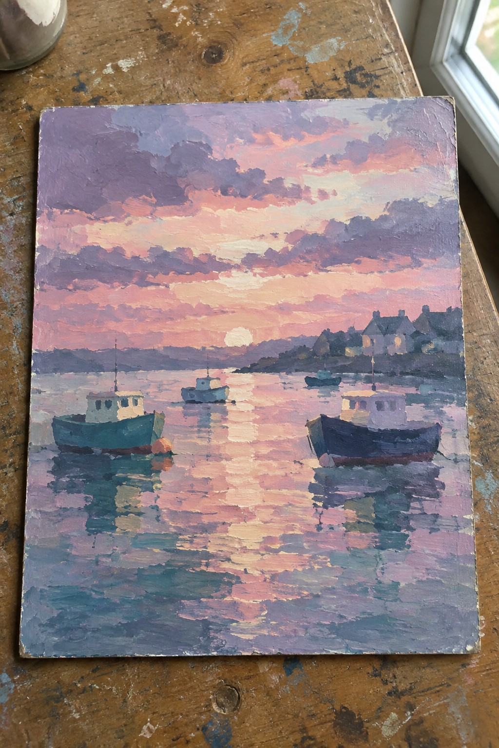 An acrylic painting of boats on calm water reflecting a pink and purple sunset with houses along the distant shore.