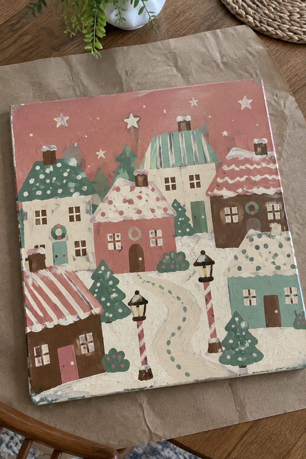Colorful painted snowy village with festive houses, wreaths, candy cane lampposts, and starry pink sky