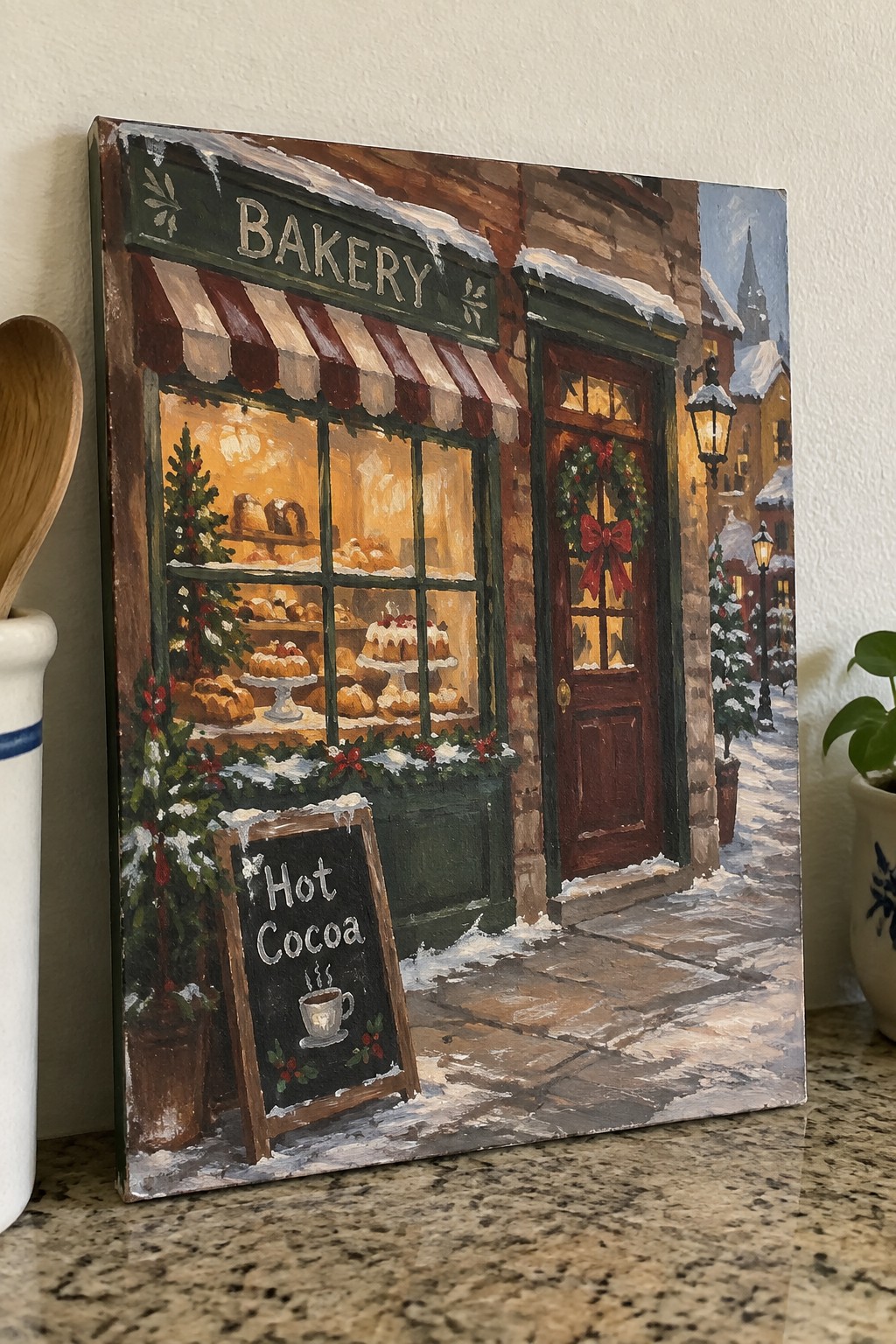Christmas bakery painting with snow, striped awning, wreath door, and hot cocoa sign