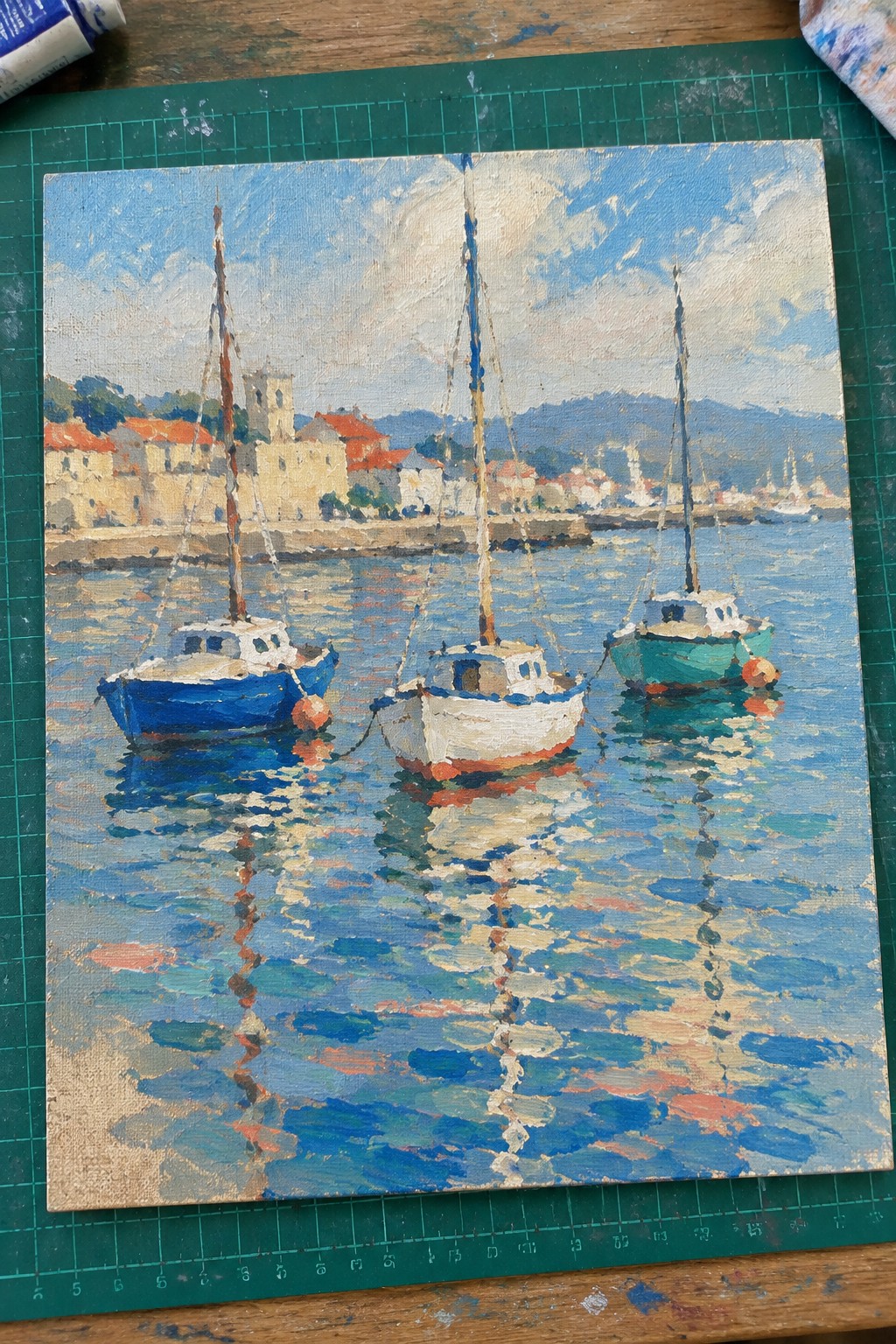 Impressionistic painting of three colorful boats moored on reflective blue harbor water.