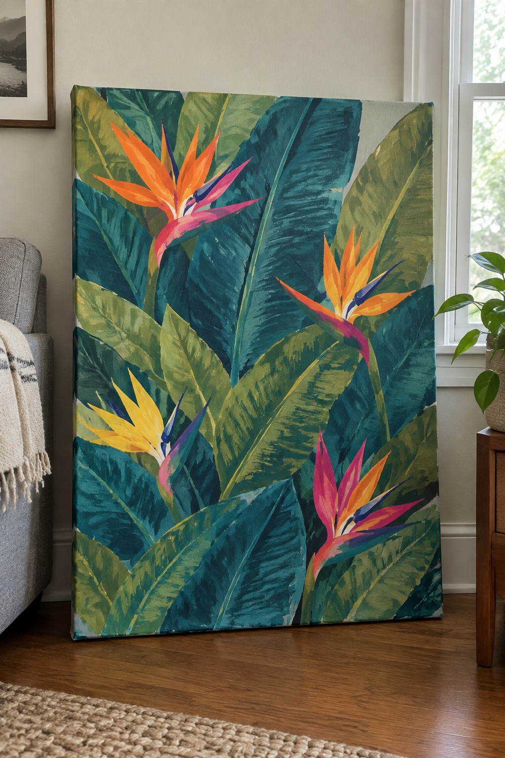Large acrylic painting of multiple Bird of Paradise flowers in bright orange, pink, and yellow with oversized green and teal leaves on a canvas leaning indoors.