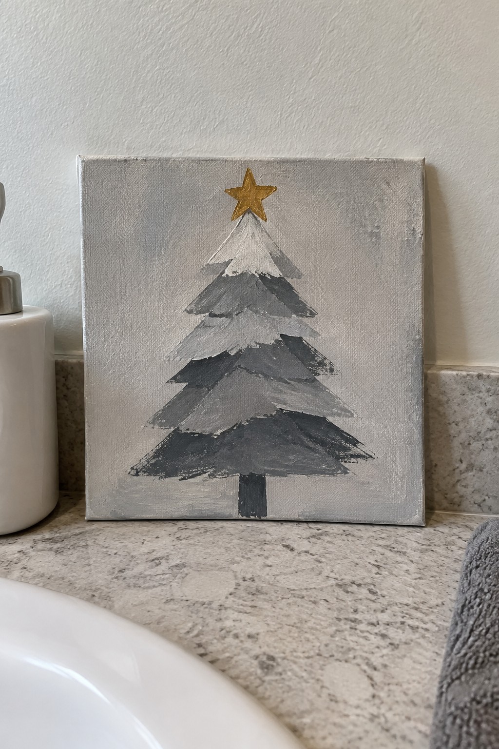 Gray Christmas tree painting with gold star on marble bathroom countertop