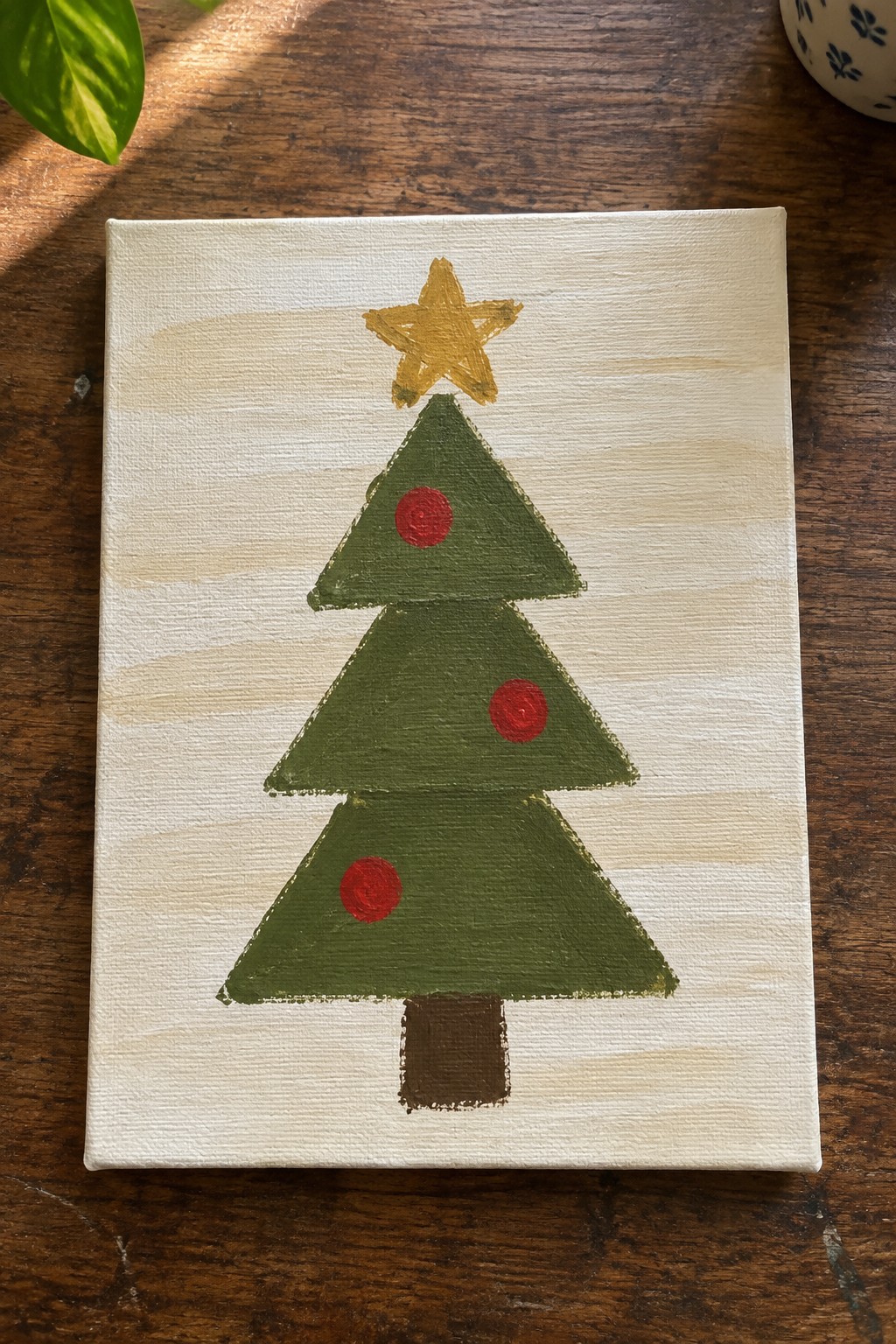 Stylized Christmas tree painting with stacked green triangles, red ornaments, and yellow star.