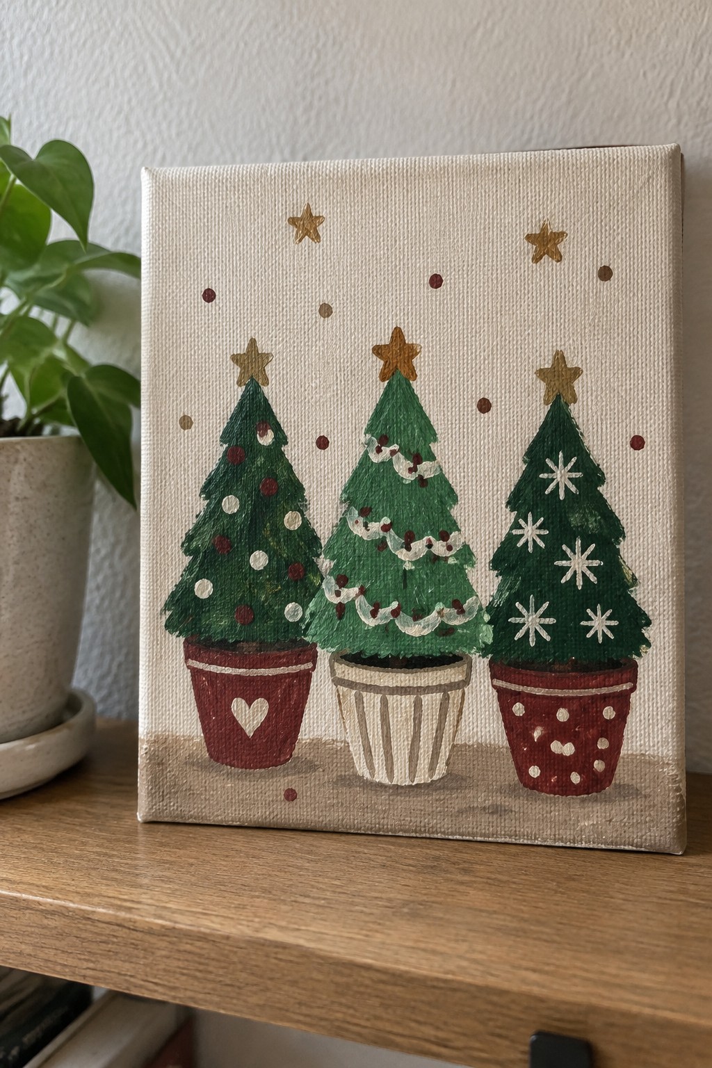 Three potted Christmas trees with gold stars on a painted canvas