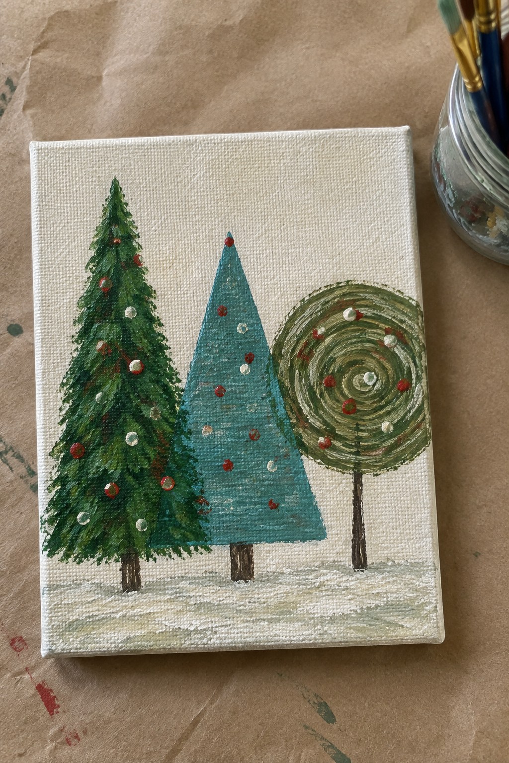 Canvas painting of three decorated trees with red ornaments on snowy ground