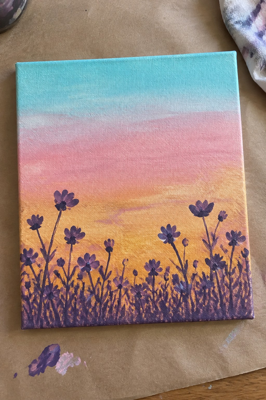 Canvas artwork of sunset gradient sky with silhouetted purple flowers at bottom
