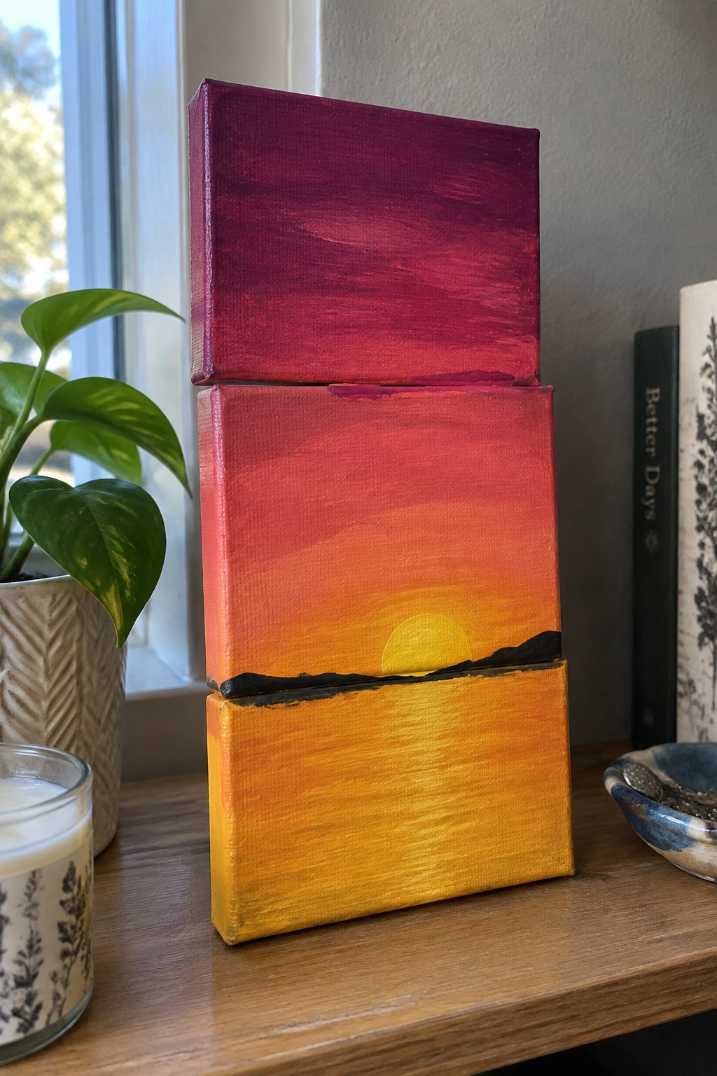 Stacked canvases form sunset gradient with yellow sun over black horizon.