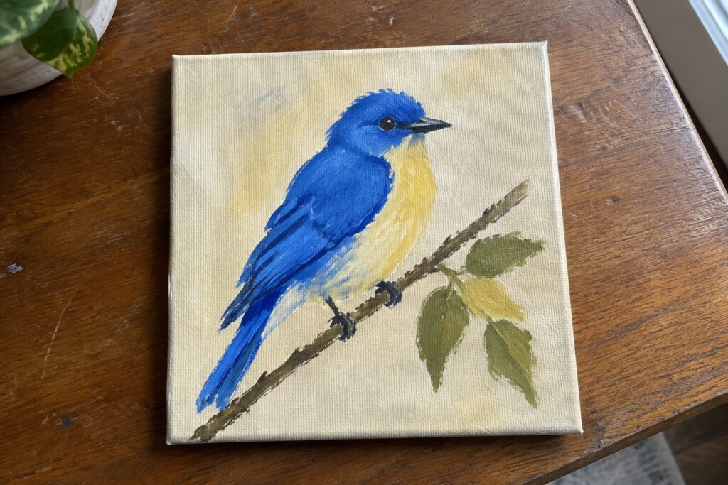 Blue and yellow bird perched on branch with green leaves on canvas