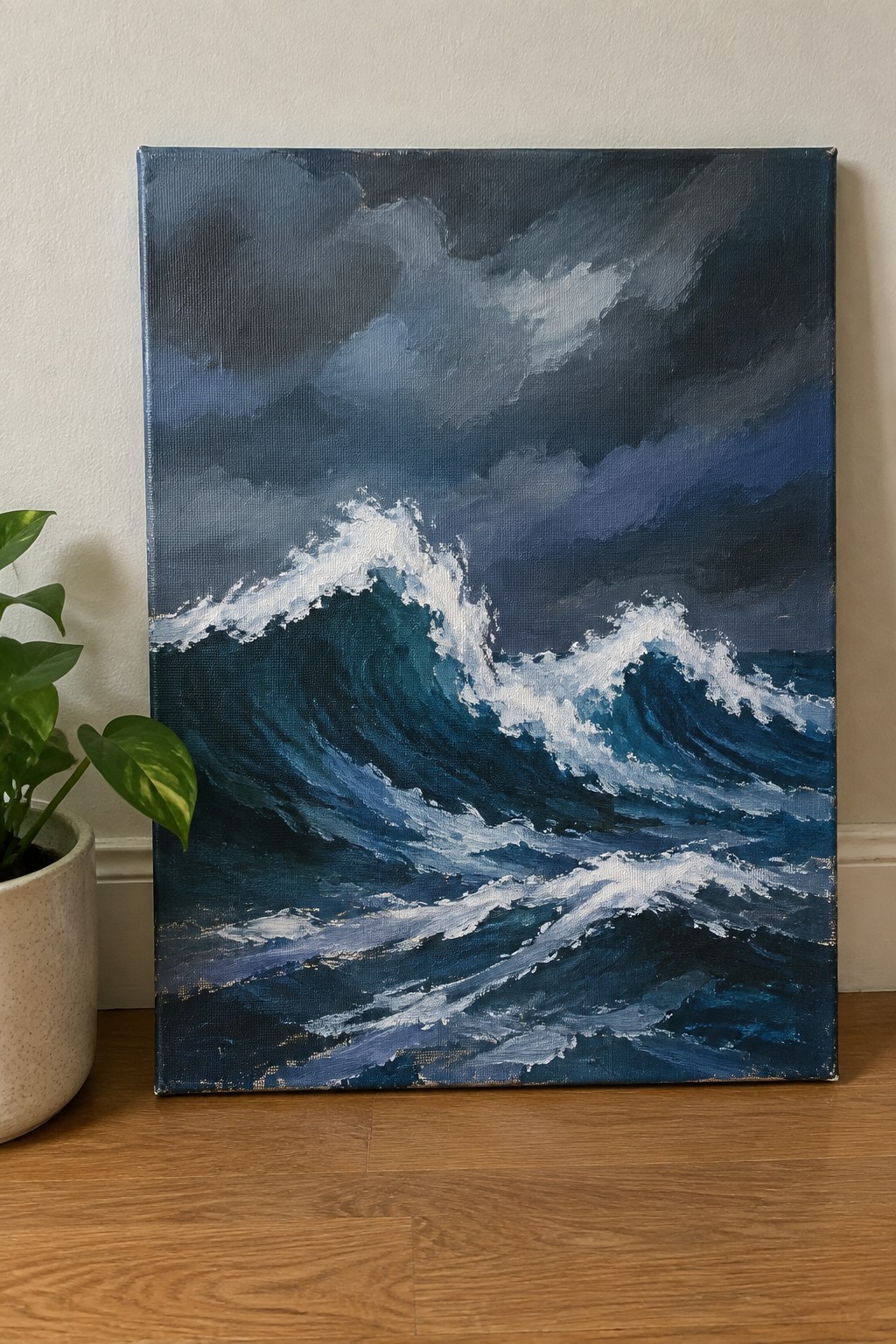 Stormy seascape painting of crashing teal waves under dark clouds beside a potted plant