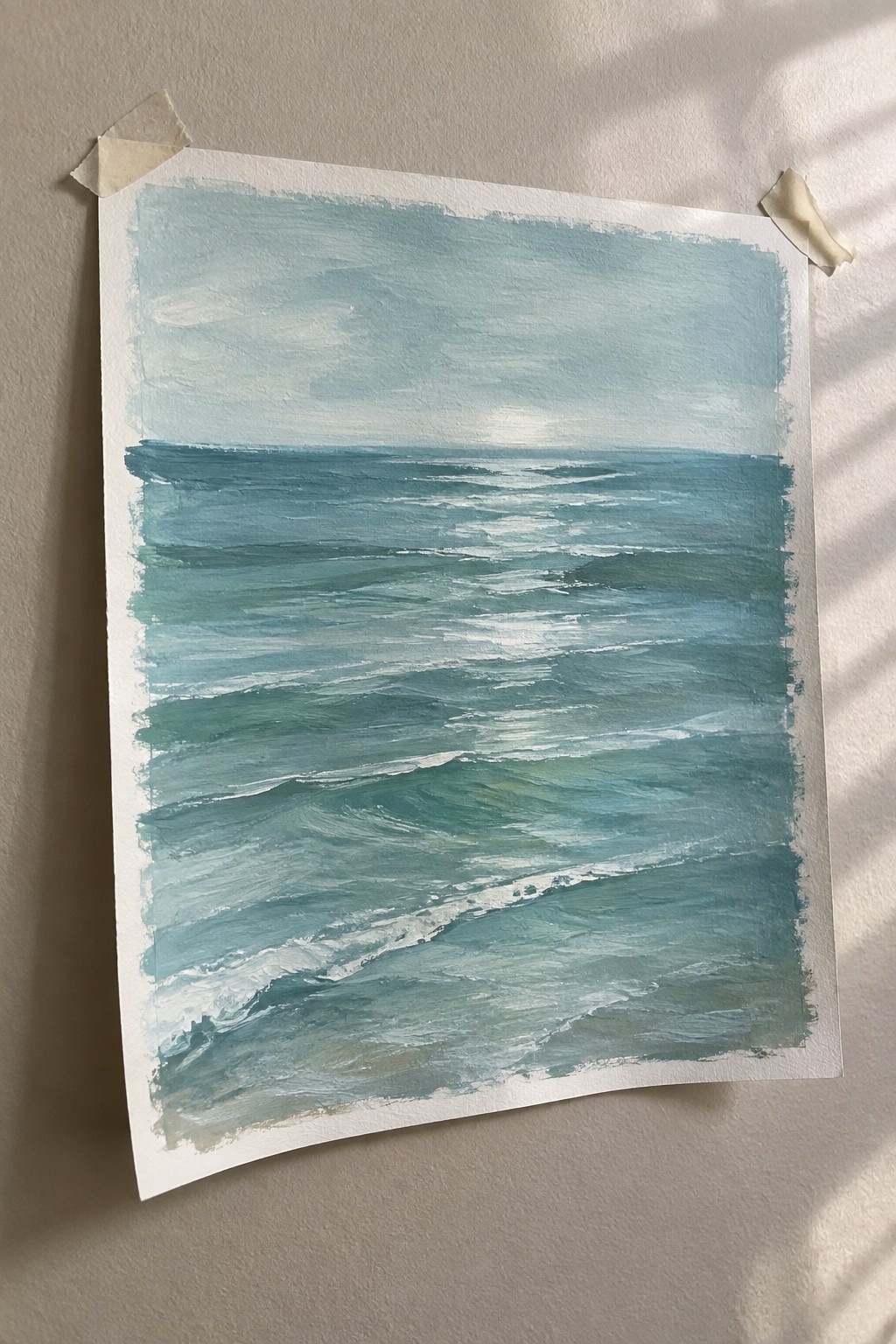Blue-green ocean waves painting taped to light wall with masking tape