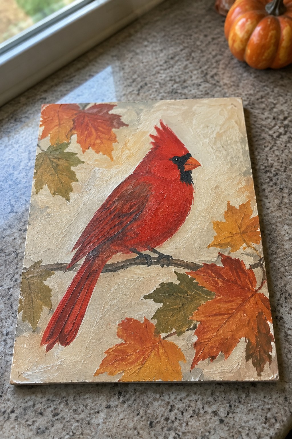 Vibrant red cardinal perched on branch amid colorful autumn maple leaves on canvas