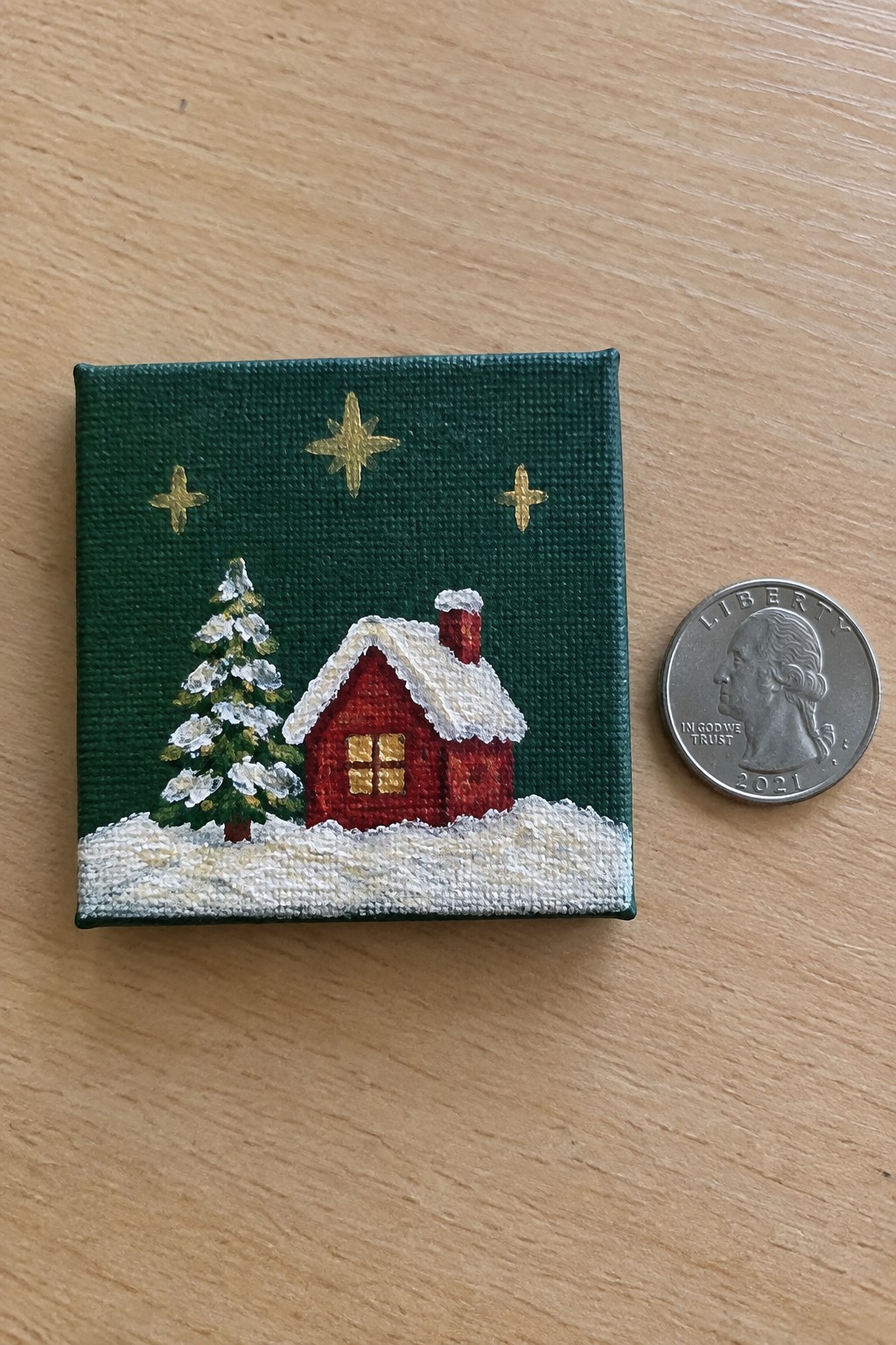 Tiny red house painting with snowy tree, gold stars, beside 2021 quarter coin